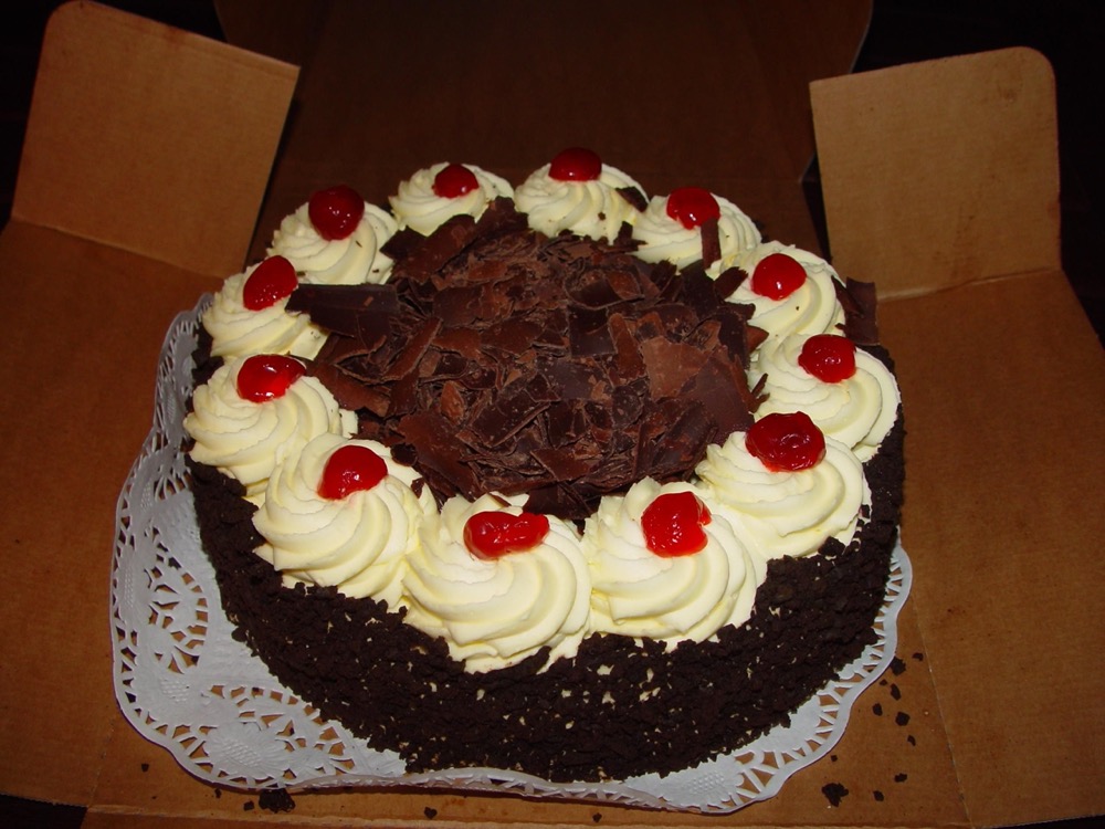 Torta decorada con crema, cerezas y virutas de chocolate
